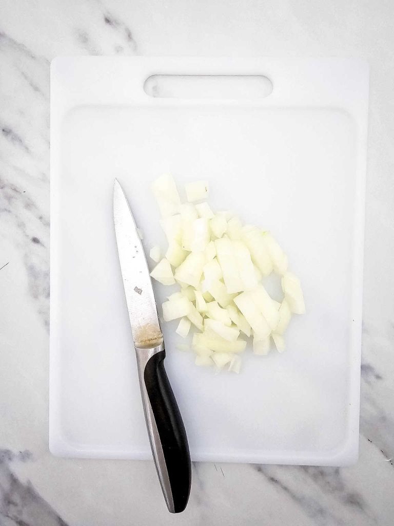 Diced onion and knife on a cutting board.