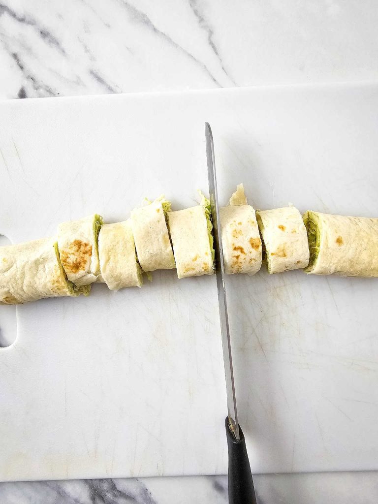 Knife and cut pinwheels on a cutting board.