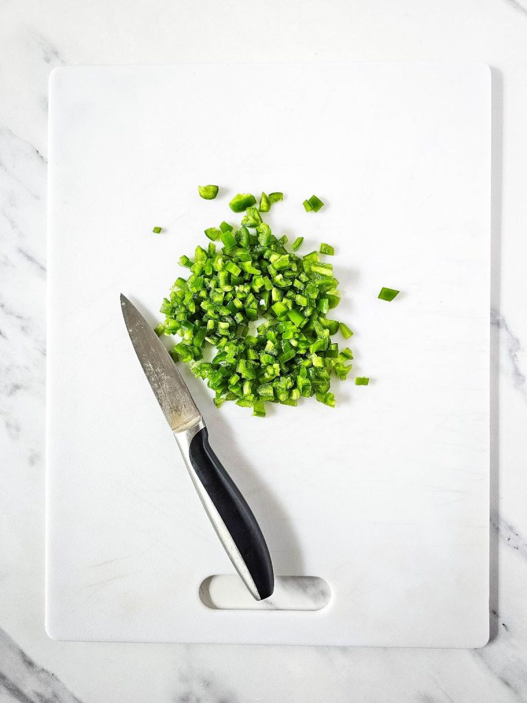 Chopped jalapeno and cutting knife on a chopping board.