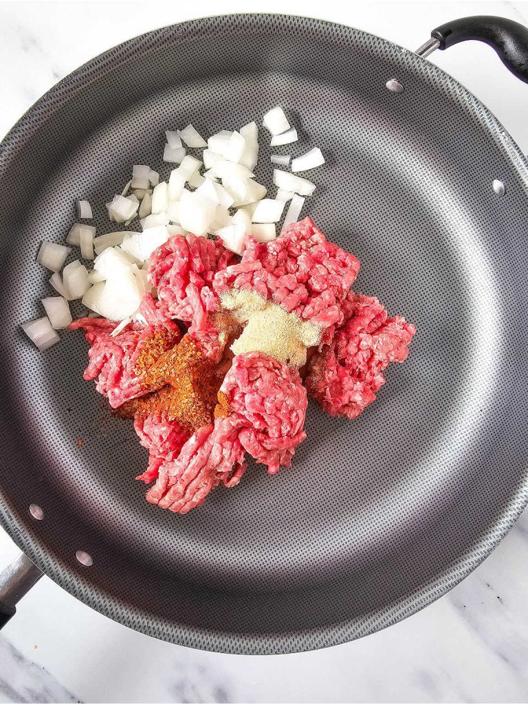 Ground beef, onion and seasoning in a skillet.