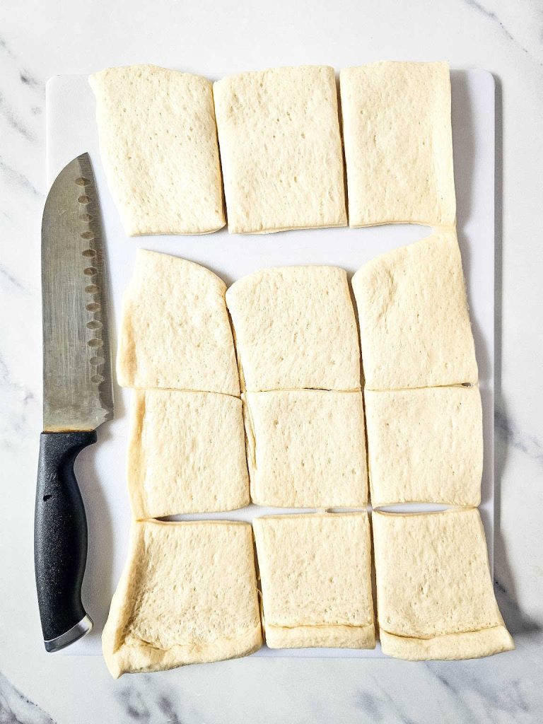 Cut pizza dough and knife on a cutting board.