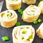 Pickle dip pinwheels on a black tray.