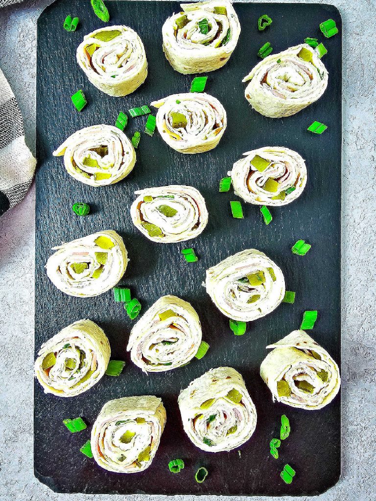 Pickle dip roll ups on a black tray.