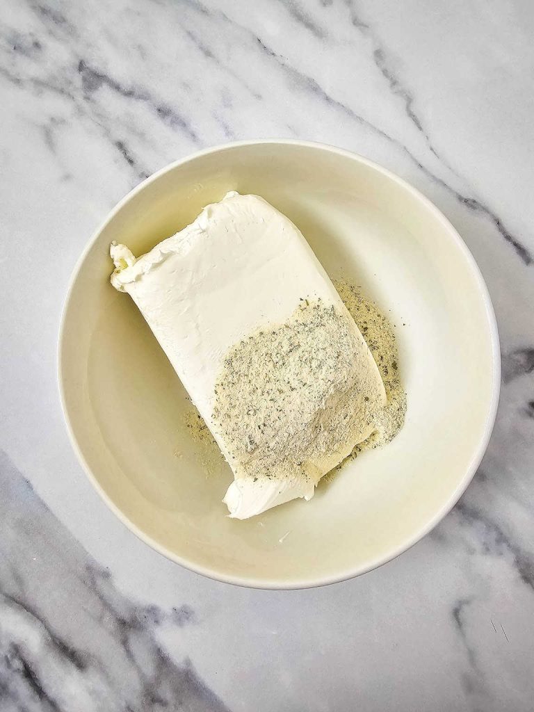 Cream cheese with the dry ranch seasoning mix in a mixing bowl.