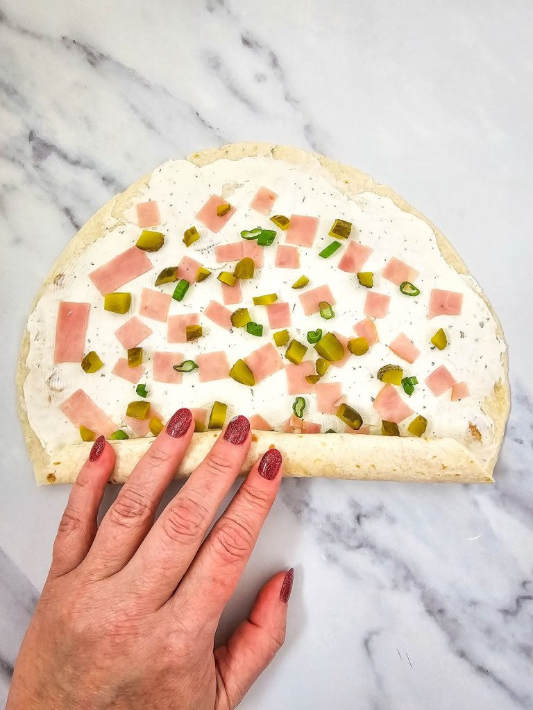 Hand rolling pickle dip pinwheel.