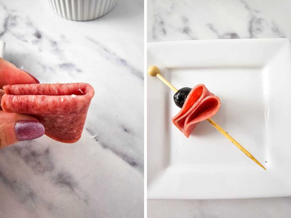 Skewered folded Salami and olive on a white plate.