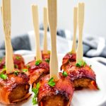 Bacon wrapped meatballs on a white platter.