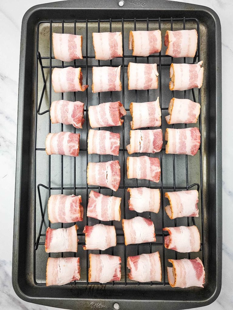 Bacon wrapped meatballs on baking rack in a baking sheet.