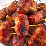 Bacon wrapped smokies on a white platter.