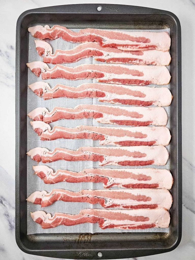 Strips of bacon on a baking sheet.