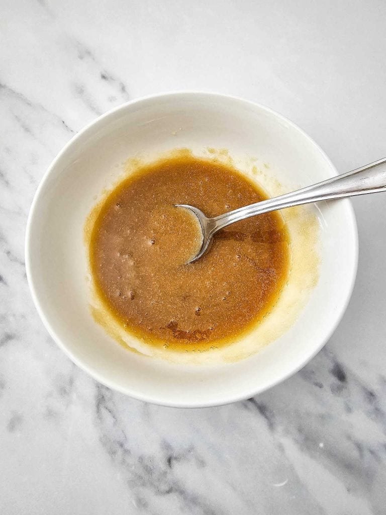 Mixture of sugar and maple syrup, and a spoon in a white bowl.
