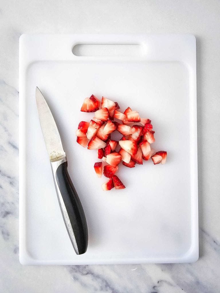  Cut strawberry pieces on a cutting board.